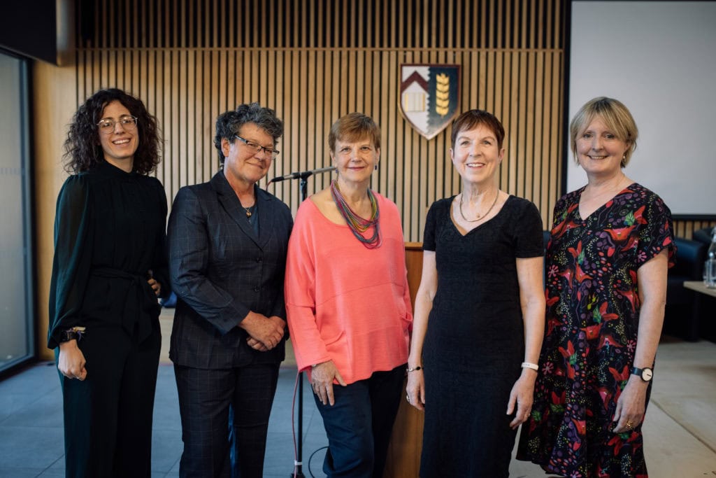 Sarah Franklin, Emily Jackson, Susan Michie, Dorothy Bishop and Helena Rodriguez Caro posing in front of the Kellogg crest