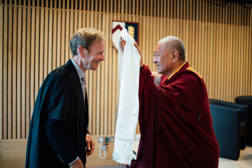 Shot from the side of Ringu Tulku Rinpoche presenting President Jonathan Michie with a Katak a traditional Tibetan ceremonial scarf