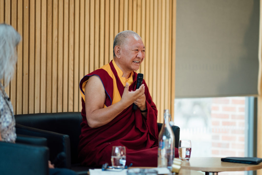 Ringu Tulku Rinpoche seated on the stage laughing and addressing the audience