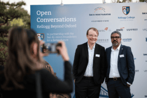 Guests and speakers standing in front of a branded sign
