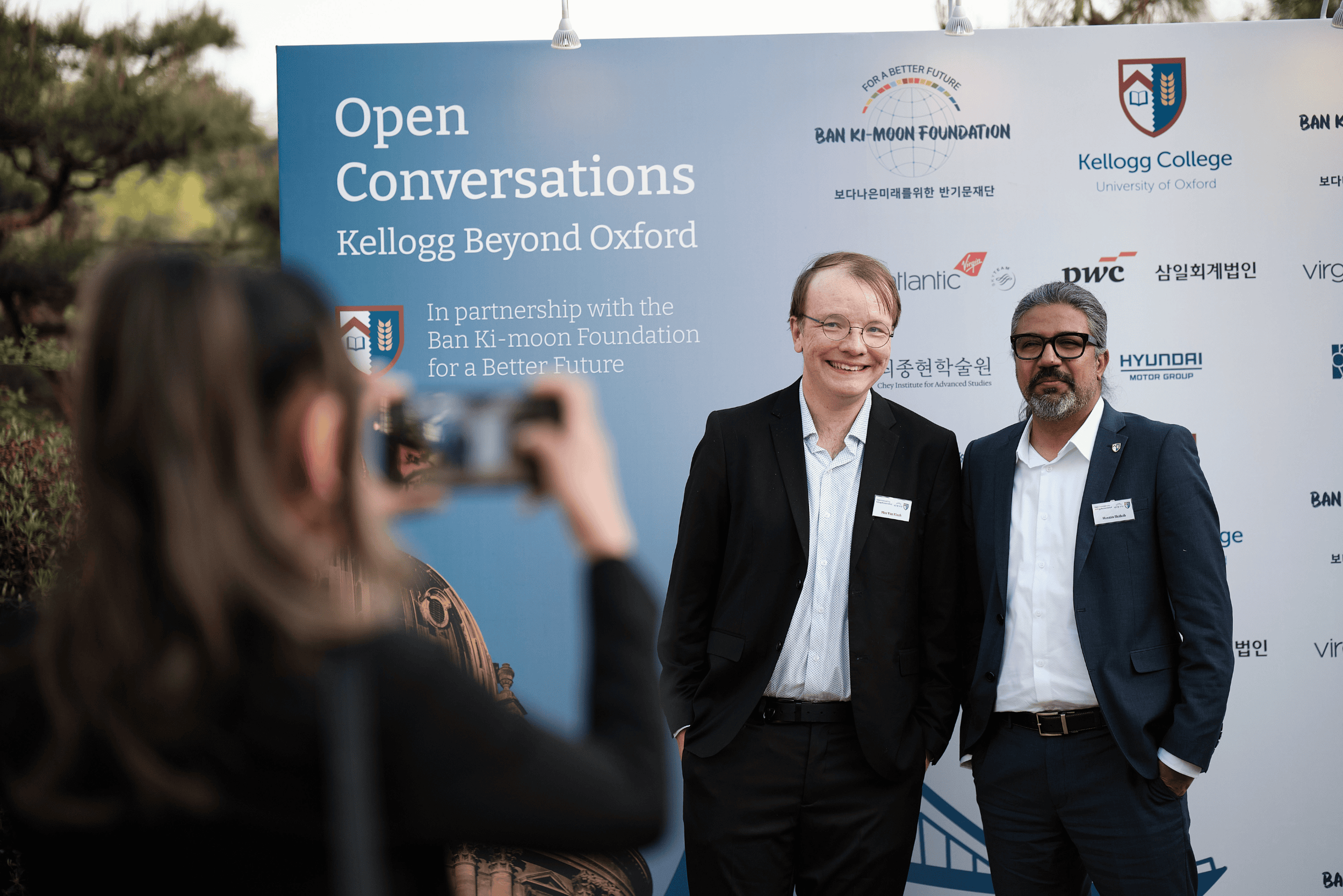 Guests and speakers standing in front of a branded sign
