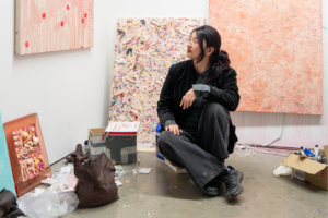 Sofia Yao sat on a stool looking at art displayed on a wall.