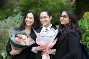Students smiling, holding bouquets of flowers