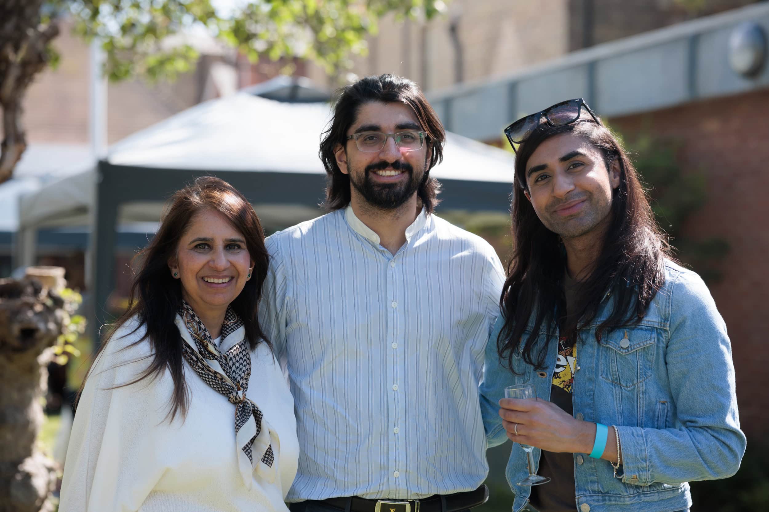 Three guests smiling for a photograph at the Summer Garden Party.