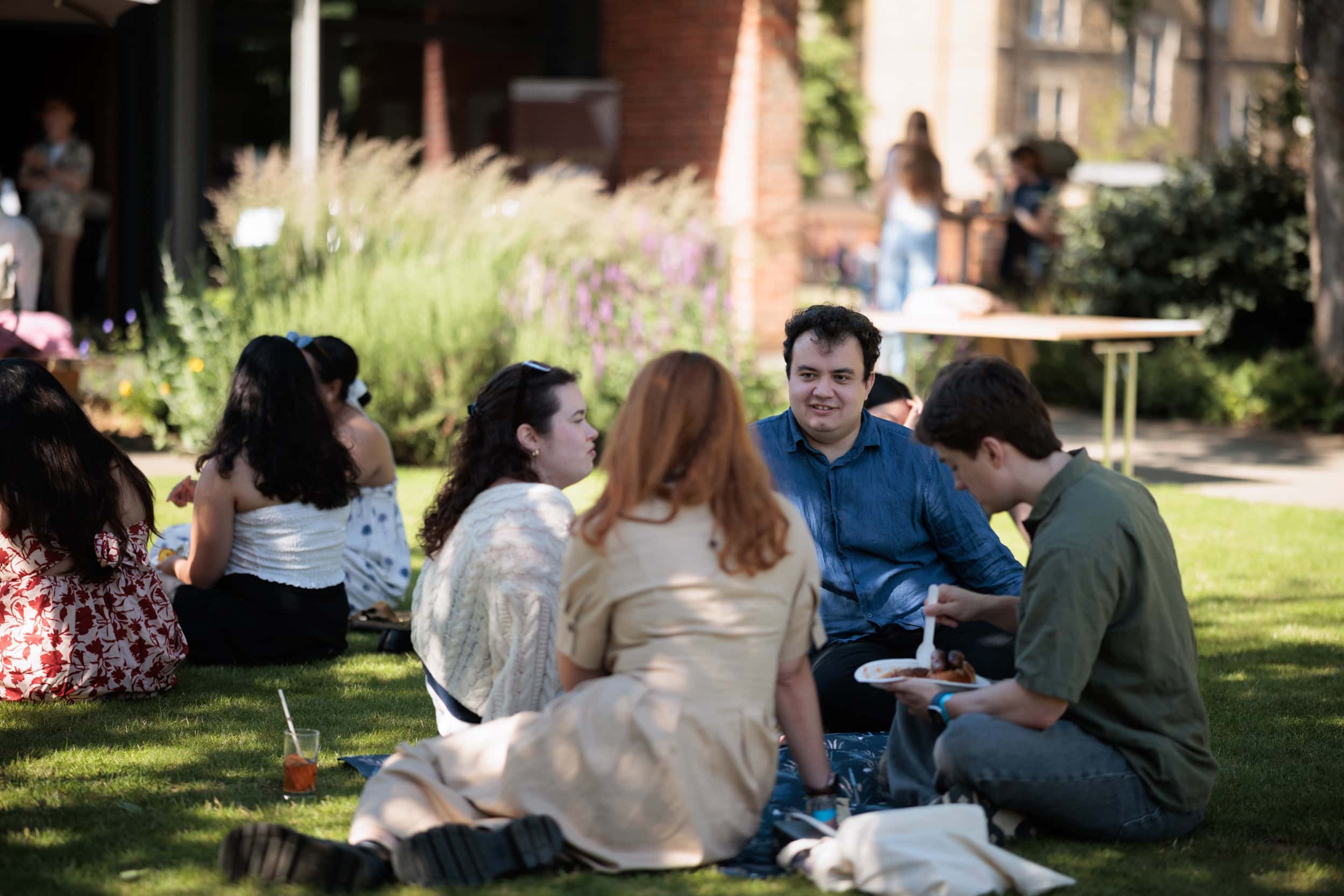 Guests seated together at picnic benches in the sunshine.
